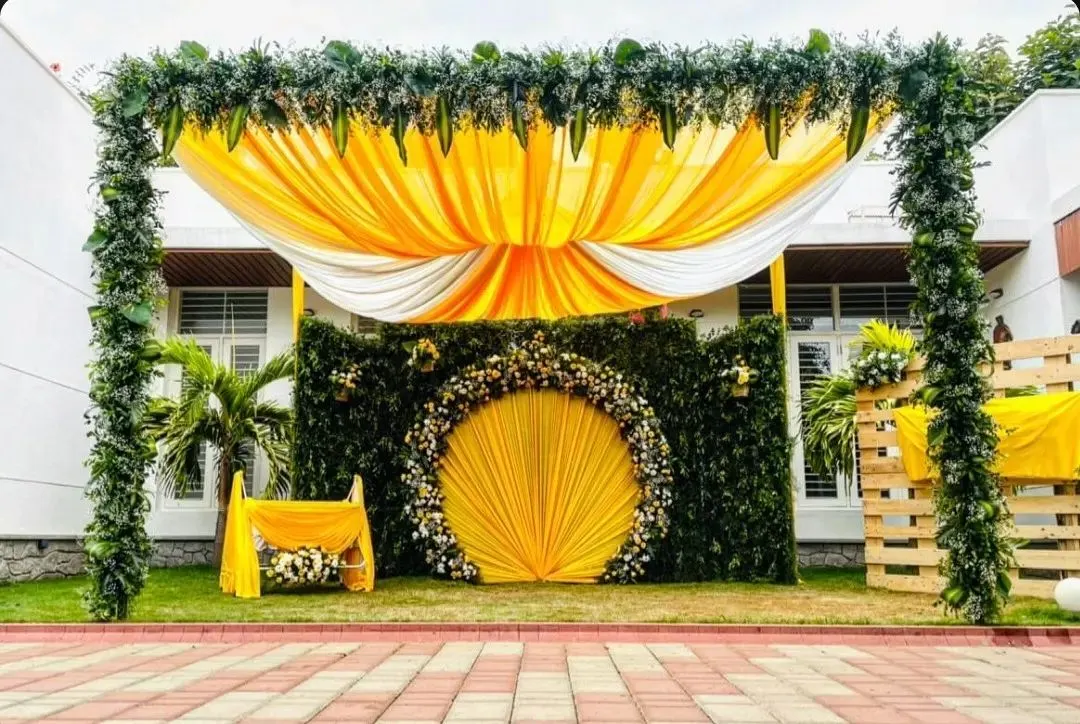 For this outdoor naming ceremony, I designed a vibrant and sunny theme. The setup features a grand arch of greenery, a backdrop of draped yellow and white fabric, and a central floral medallion, creating a beautiful focal point on the lawn.