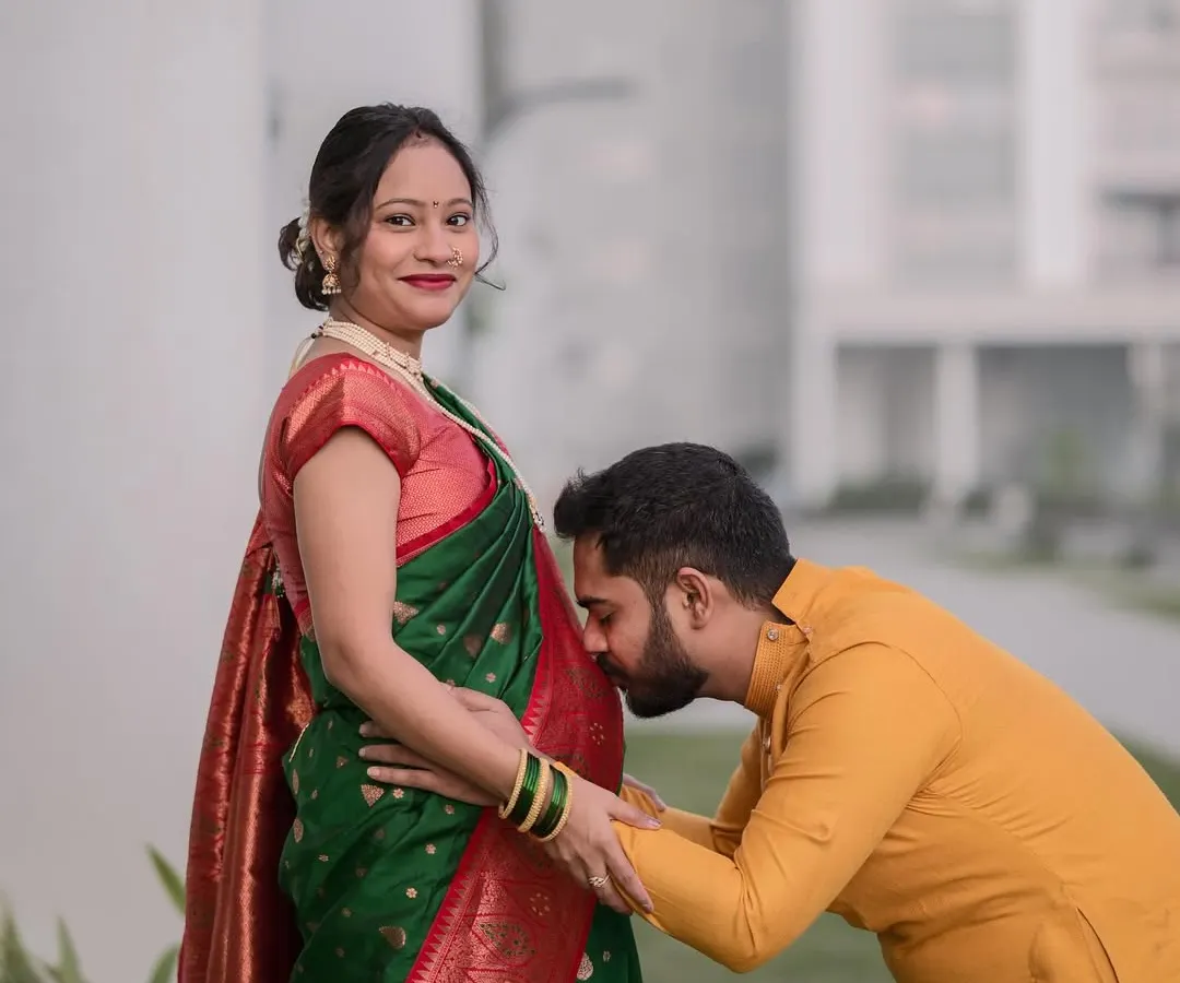 A classic and tender maternity portrait of a husband-to-be kissing his wife's baby bump. This outdoor pregnancy photoshoot in Bangalore captures the couple's love and excitement in a natural setting.