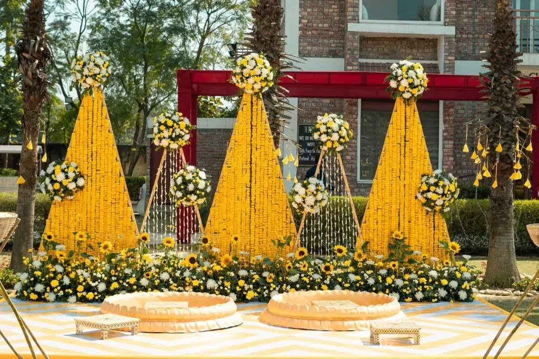 We believe a Haldi ceremony should be drenched in happiness and colour. This outdoor setup features towering cones of bright yellow marigolds, sunflower accents, and traditional seating, creating a picture-perfect scene for a sun-kissed celebration.