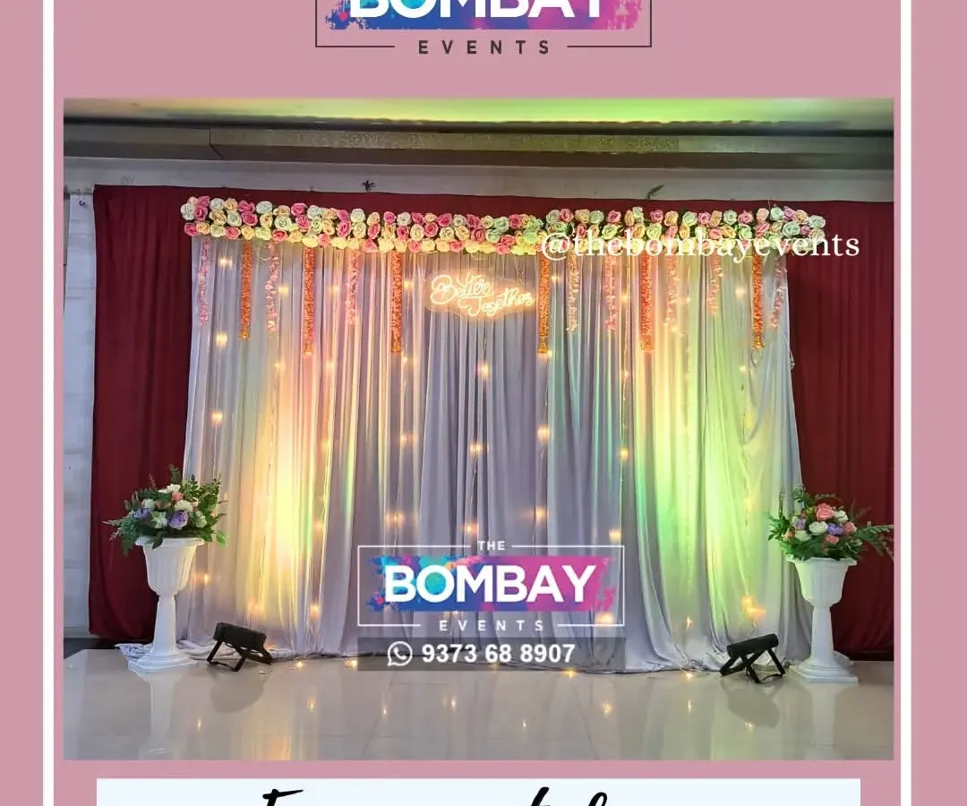 For this engagement ceremony, we designed an elegant stage backdrop using flowing white and red drapes, warm fairy lights, and a beautiful floral arrangement on top. The uplighting adds a touch of drama, making the couple the center of attention.