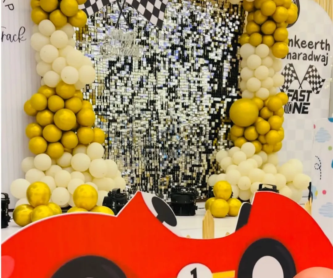 Full throttle for a first birthday with this "Fast One" racetrack theme. A shimmering sequin backdrop, balloon arches in gold and white, and a fun car cutout create an exciting and playful atmosphere for a little speedster's big day.