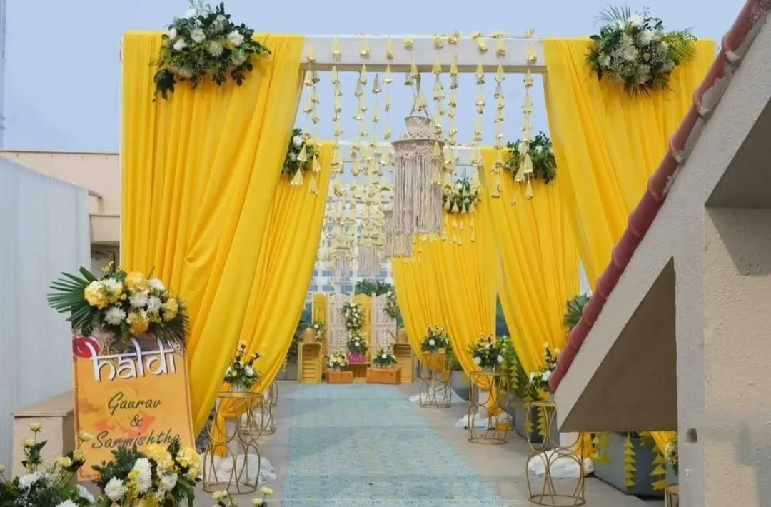This is the entrance to a vibrant Haldi ceremony I decorated on a rooftop in Lodha. The bright yellow drapes, hanging floral strings, and fresh flower arrangements create a welcoming and festive atmosphere for the celebration.