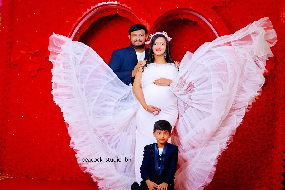 Celebrate your journey to motherhood with the whole family. This photo showcases a beautiful white maternity gown with dramatic ruffled wings, with coordinating outfits for your partner and child.