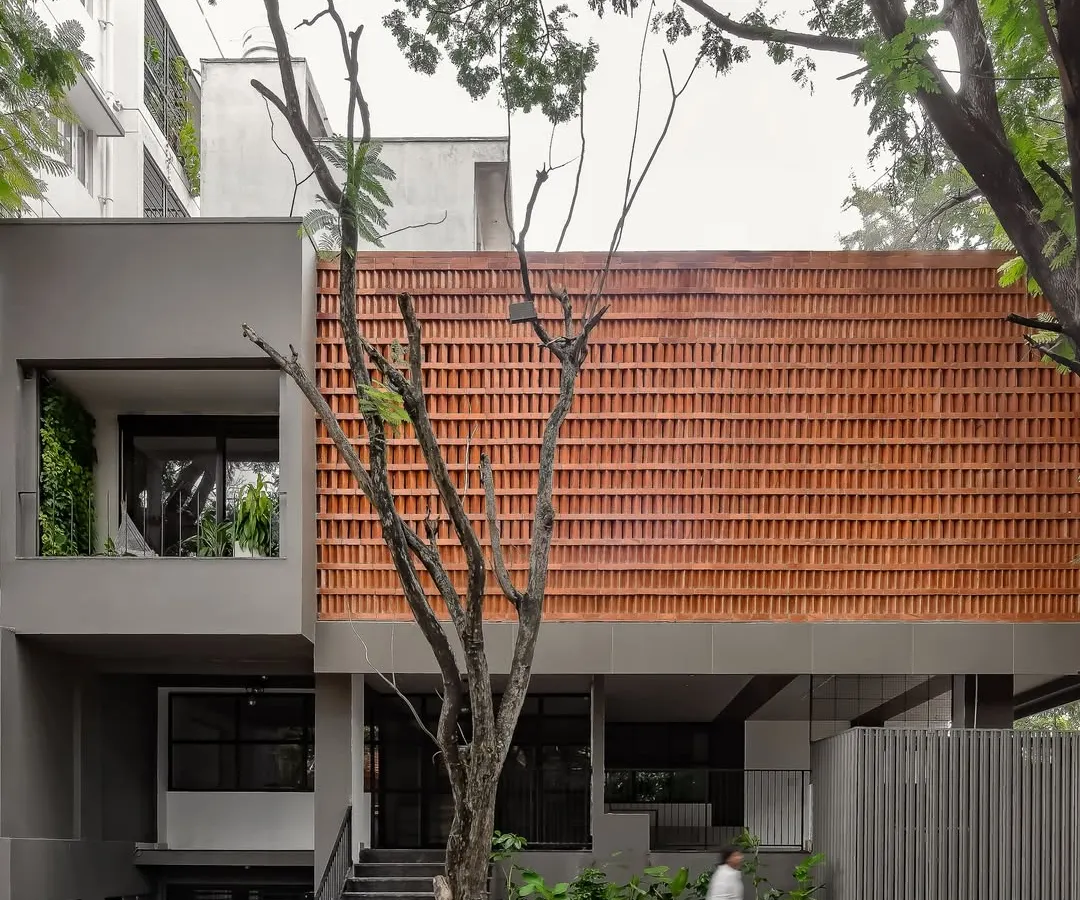 This is our own studio, Akshara Vinyasaa, where our design philosophy comes to life. The facade features a screen of locally sourced terracotta bricks, a climate-responsive element that provides natural cooling while creating a visual connection to the earth.