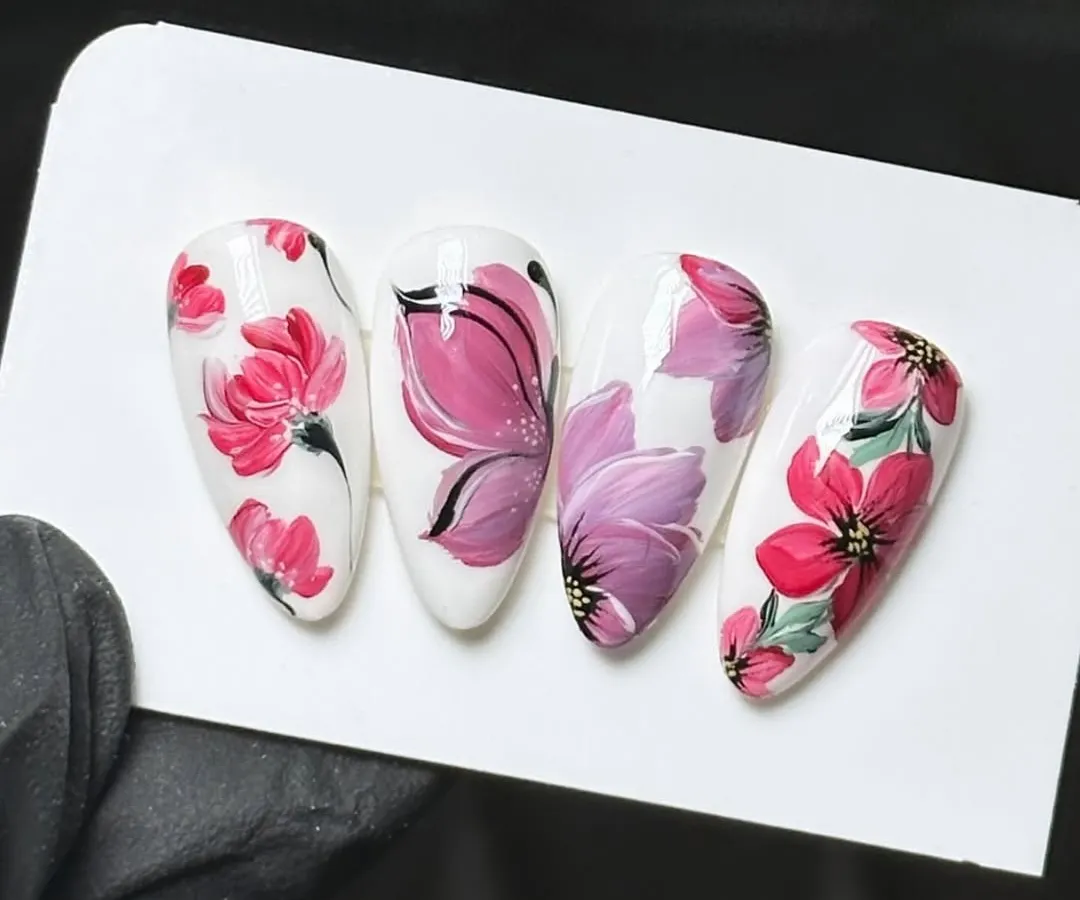 This is the level of detail and artistry my students achieve. This example of student work shows intricate, hand-painted floral designs on almond-shaped nail tips, demonstrating the high-quality techniques taught in my nail art design workshops.