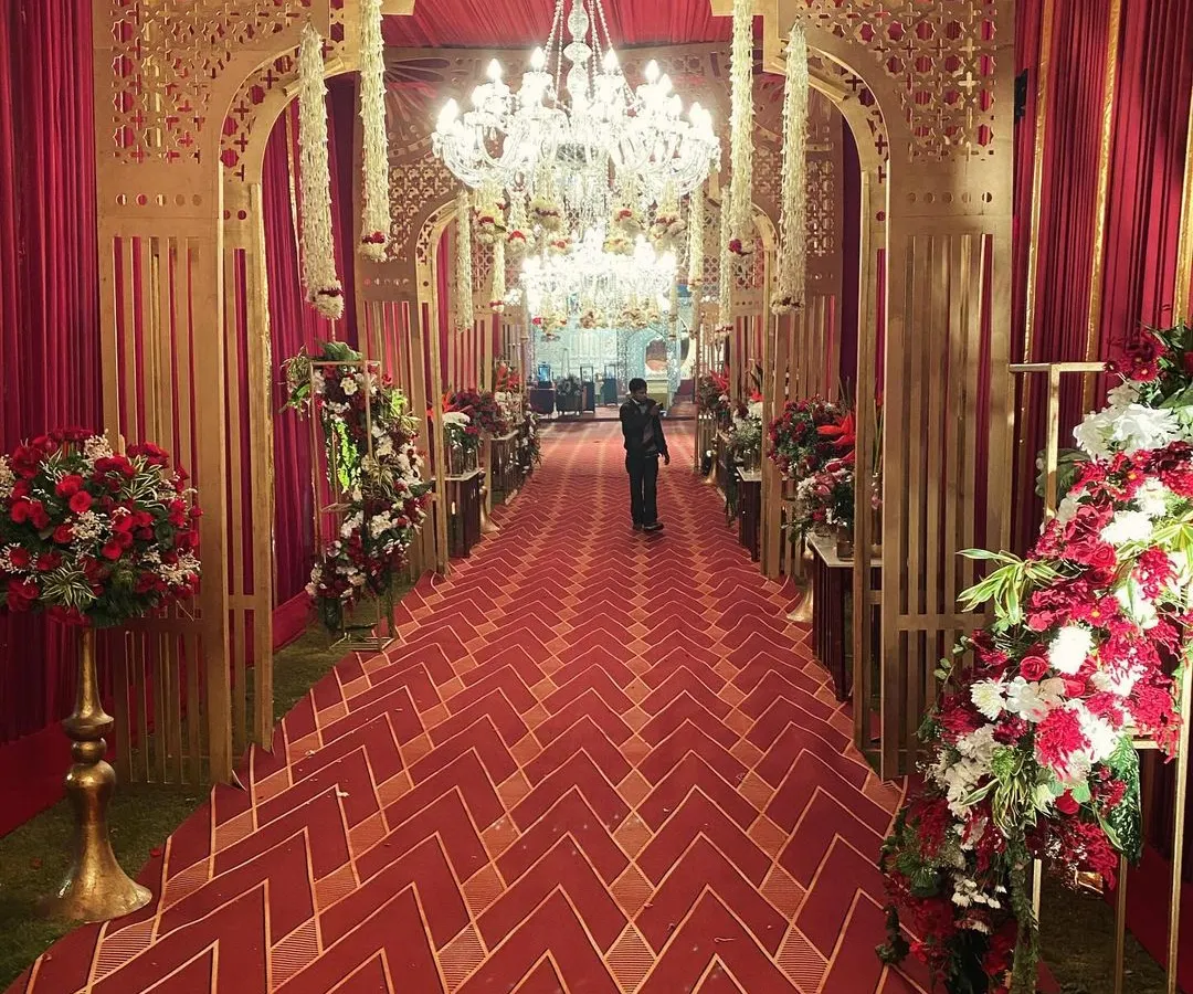 For those who dream of timeless grandeur, I craft entrances that speak the language of royalty. This opulent passageway for a royal Indian wedding features intricate gold-lacquered arches, magnificent chandeliers, and a rich red carpet, setting a majestic tone from the very first moment.