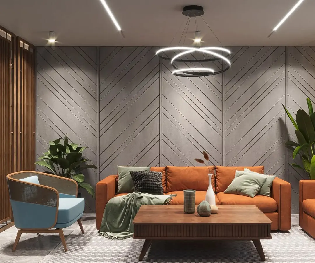 A modern living area designed for comfort and style. The room features a bold orange sofa, a textured concrete accent wall with diagonal grooves, and contemporary lighting fixtures, creating a vibrant yet sophisticated space for relaxation and socializing.