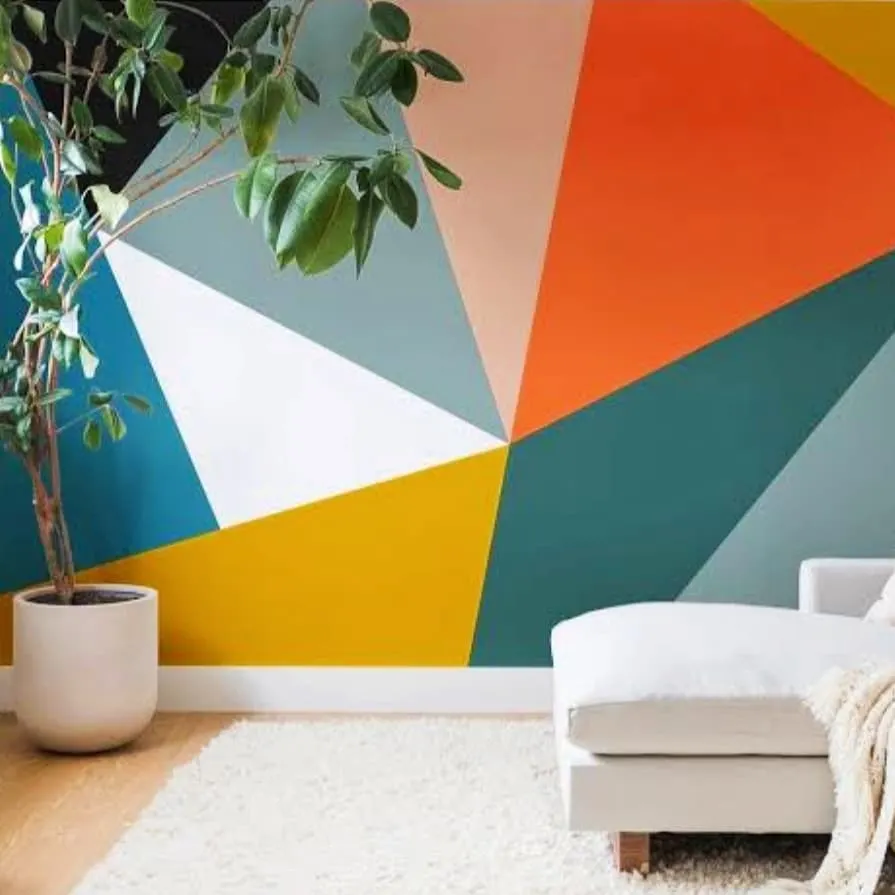 This living room features a dynamic geometric accent wall, using a bold palette of orange, yellow, and teal. This type of colour blocking is a modern way to inject personality and energy into a room, turning a plain wall into a work of art.