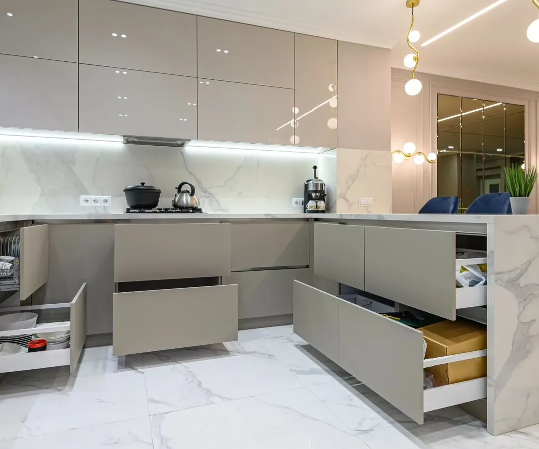 A modern kitchen is the heart of the home, and we design them for both beauty and function. This space features a minimalist aesthetic with handle-less high-gloss cabinets, a marble-finish countertop, and smart, soft-close drawers that reveal maximum storage, ensuring a clutter-free and premium cooking experience.
