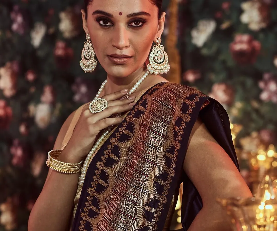 The epitome of bridal grace. This image captures the intricate zari work on the pallu of a deep blue Banarasi silk saree, a classic choice for wedding ceremonies and receptions, paired with traditional pearl jewelry.