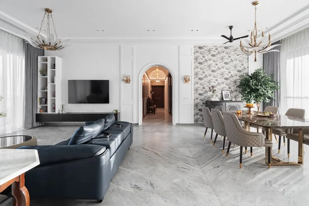 This expansive living and dining area is a perfect example of modern luxury. We used a foundation of white marble flooring and classic wall mouldings, then layered in a deep blue leather sofa and elegant chandeliers to create a space that feels both grand and welcoming.