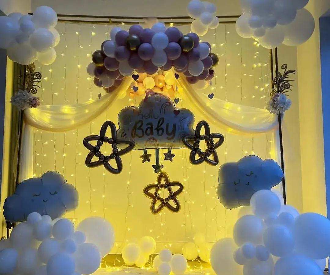 We brought a dreamy sky indoors for this baby shower. The setup features fluffy white balloon clouds, a warm backdrop of fairy lights, and a central balloon arrangement in pink and gold, creating a magical and serene atmosphere for welcoming the little one.