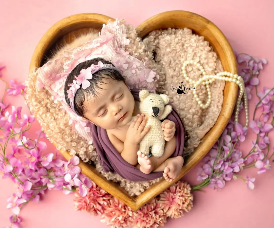 A newborn peacefully dreaming in a heart-shaped bowl, surrounded by soft pinks. This is the kind of timeless, gentle portrait I love to create in those magical first few days.