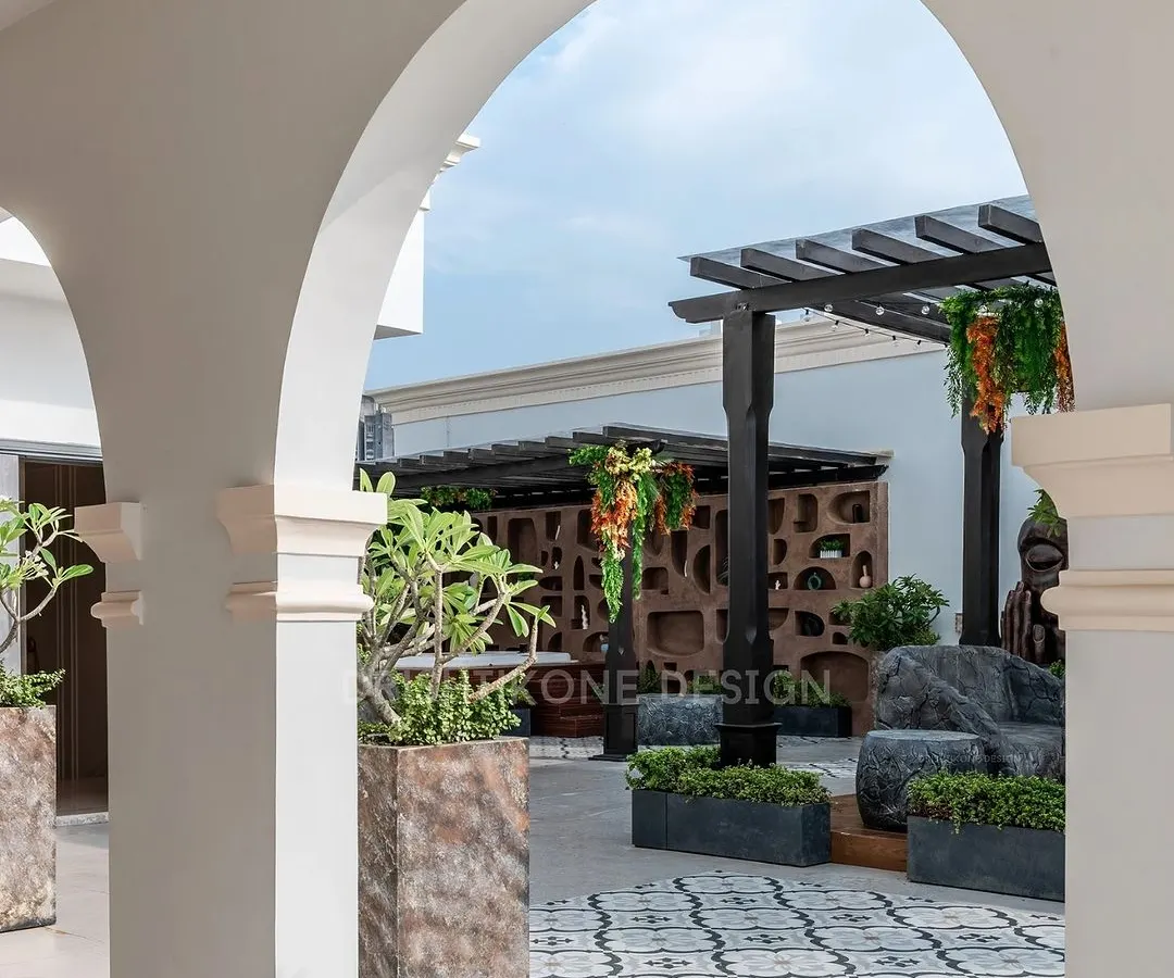 We transformed this empty rooftop into a serene escape. This view, framed by classic arches, showcases the custom pergola, intricate tilework, and lush planters that create a perfect oasis for relaxation and entertainment right at home.