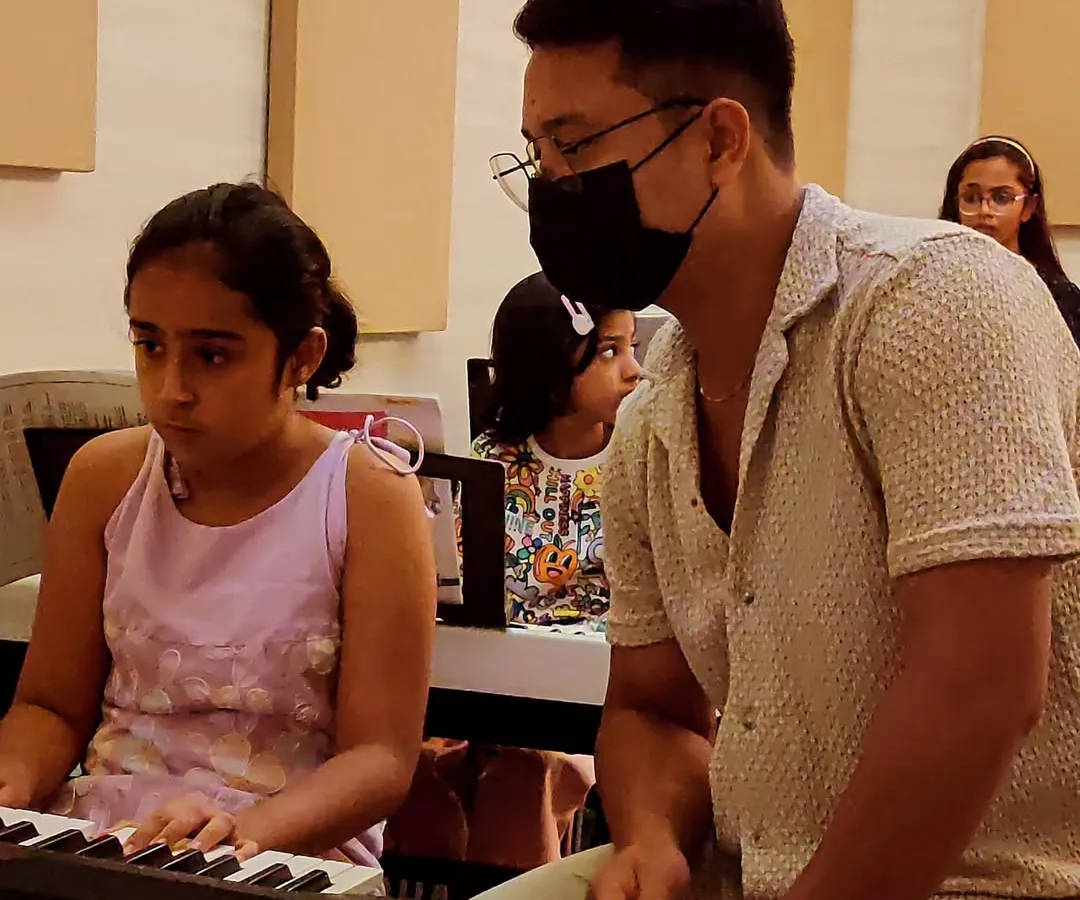 Here is a glimpse into our one-on-one keyboard lessons. Our instructor provides personalized guidance to a young student, focusing on proper technique and fostering concentration in a supportive classroom environment.