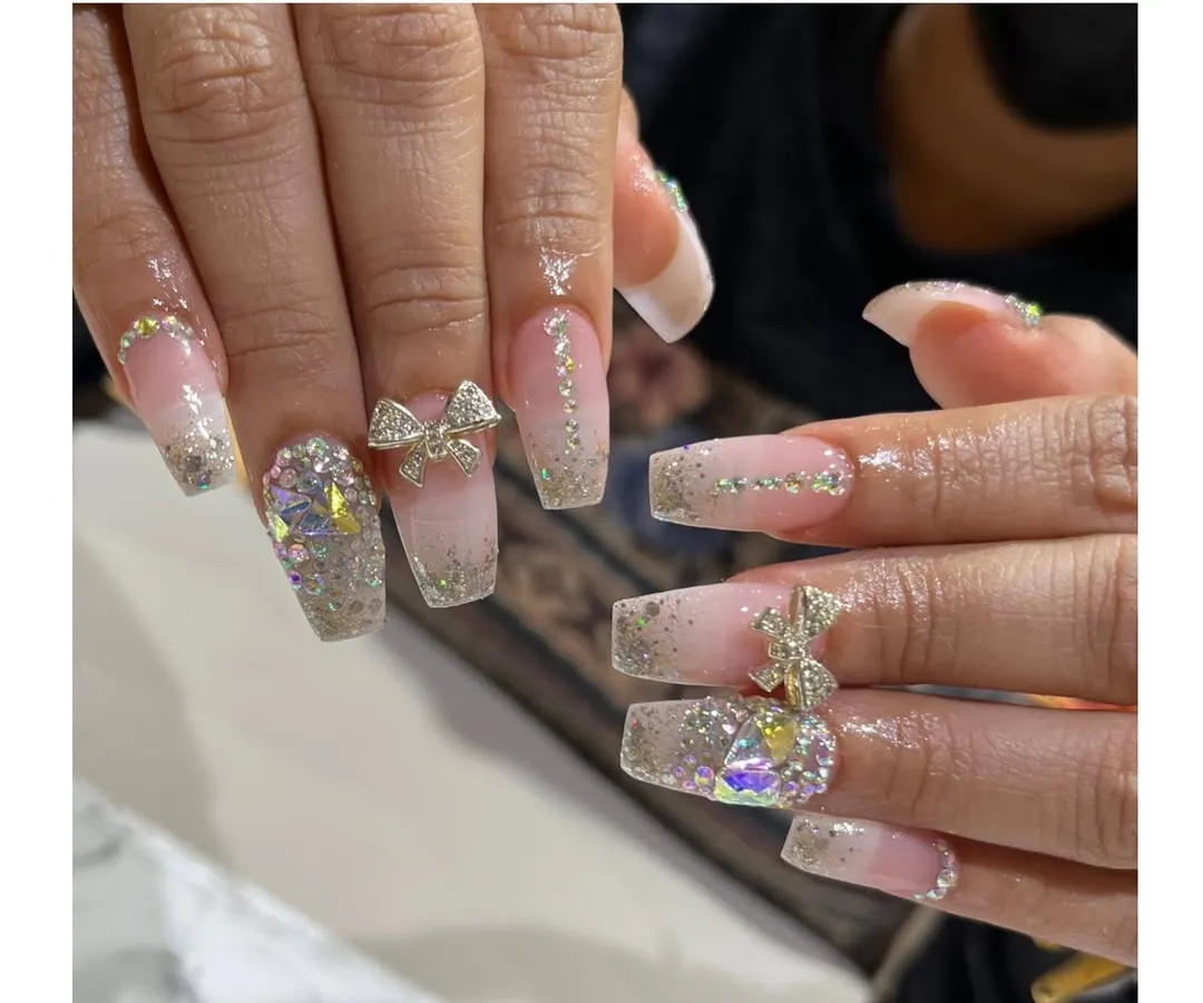 For our brides, we create unforgettable nail art. This design features long, square-shaped extensions with a glitter base, sparkling rhinestones, and delicate 3D bow embellishments for a truly special day.