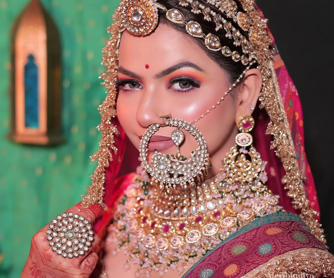 Mastering traditional bridal hairstyling is a key to success. This Rajasthani bridal look showcases intricate hair work, including the placement of a traditional matha patti and a heavily jeweled nath, complementing the overall regal aesthetic.