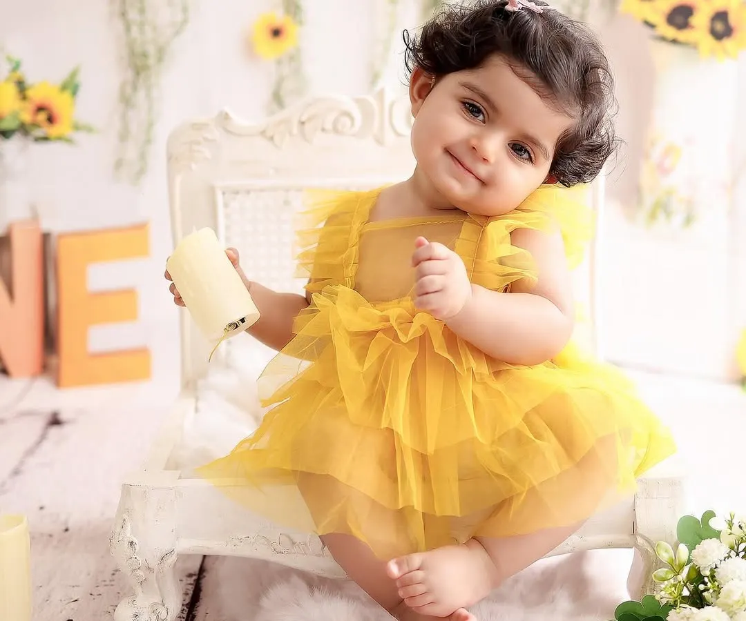 Before the cake, we capture timeless portraits. Here, a beautiful baby girl shines in our popular sunflower-themed set, complete with a matching yellow dress.
