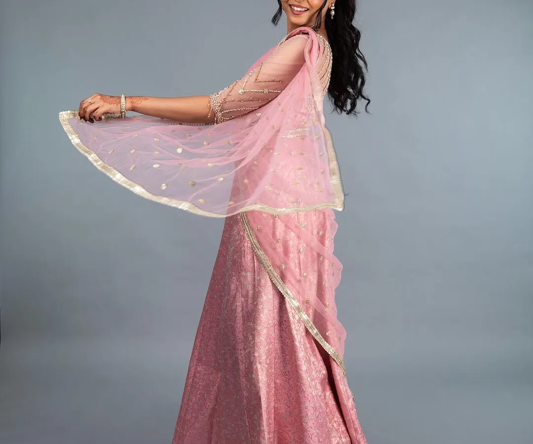 A full view of our stunning pink brocade lehenga. The lightweight fabric and elegant drape make it perfect for twirling on the dance floor at a sangeet or reception. The custom-fit blouse features delicate sleeve detailing, completing this graceful and timeless look.