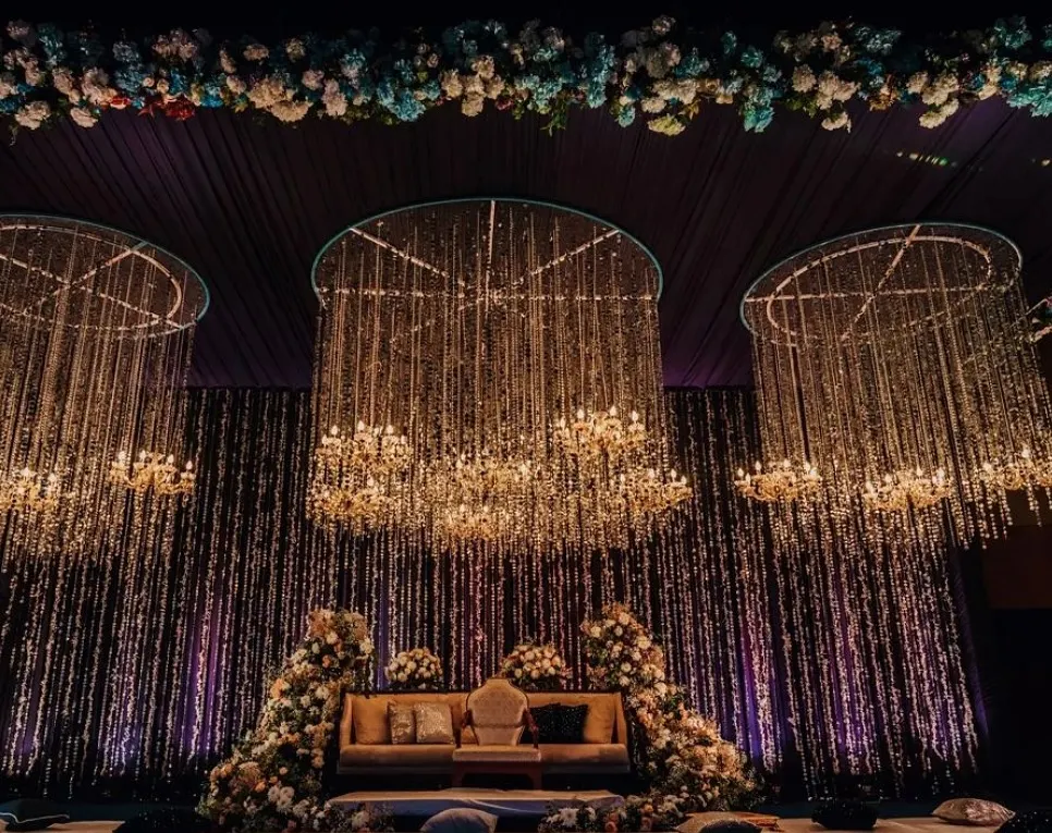 We create magical Sangeet nights with dramatic lighting and opulent decor. This stage features a cascade of crystal chandeliers against a dark, moody backdrop, perfect for an evening of music and celebration.