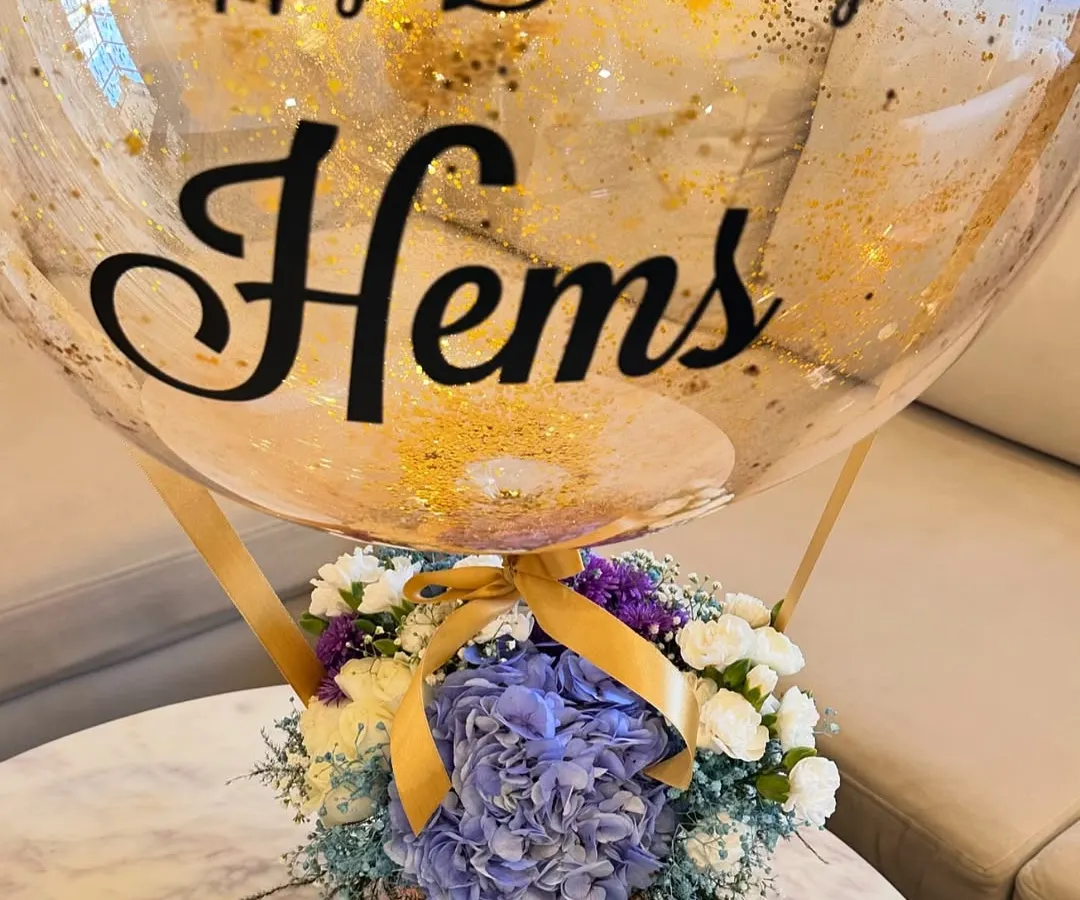 My signature hot air balloon arrangement is a client favorite. Here, I paired a beautiful box of blue hydrangeas, white roses, and carnations with a custom gold-flecked bubble balloon for a special birthday celebration.