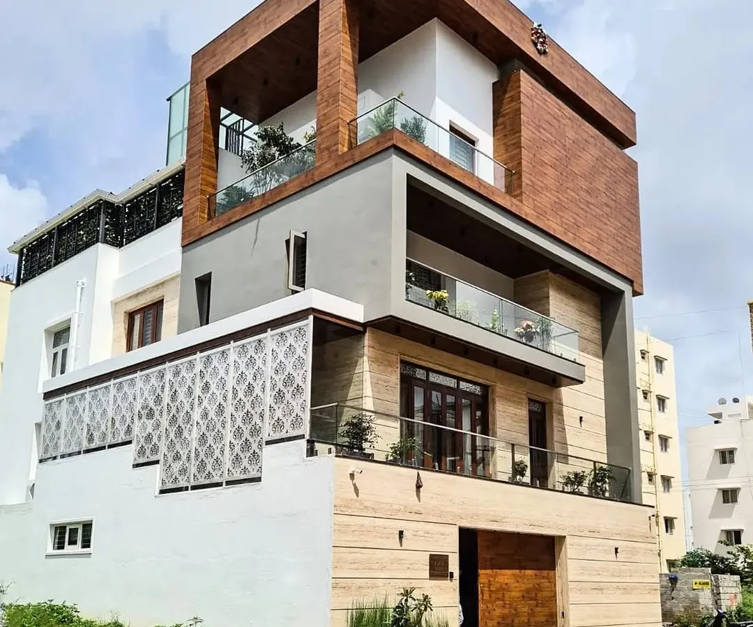 This is a completed residence in AECS Layout, showcasing a powerful contemporary elevation. The design features a prominent wood-clad cube, natural stone at the base, and delicate jalli screens, demonstrating my approach to using mixed materials for texture and character.