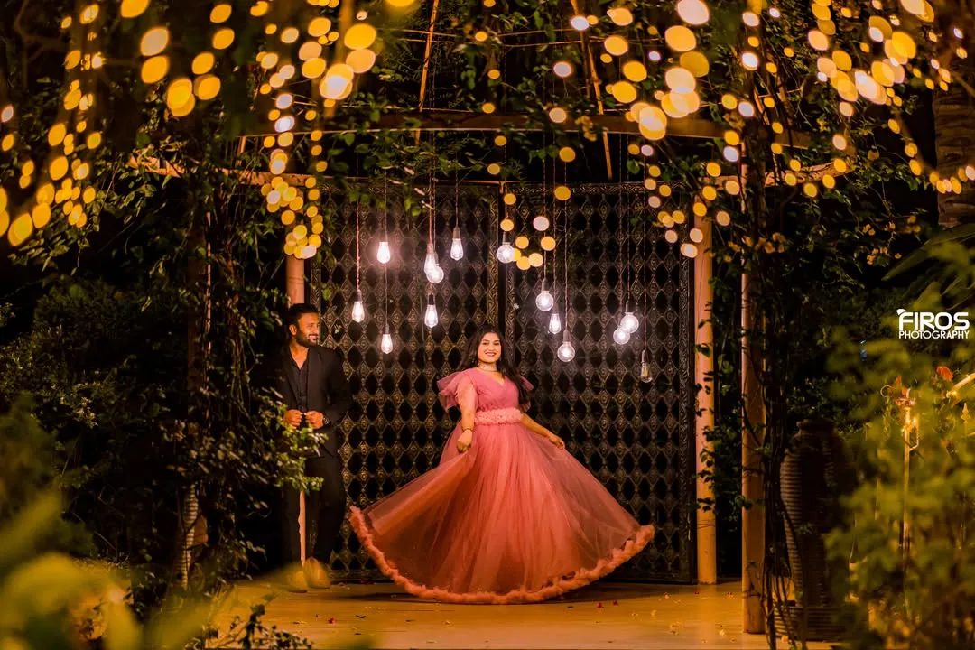 As night falls, we use the magic of light to create a truly romantic atmosphere. This shot, framed by a canopy of warm lights, shows how we can craft an intimate, dreamy portrait that feels like a scene from a movie.