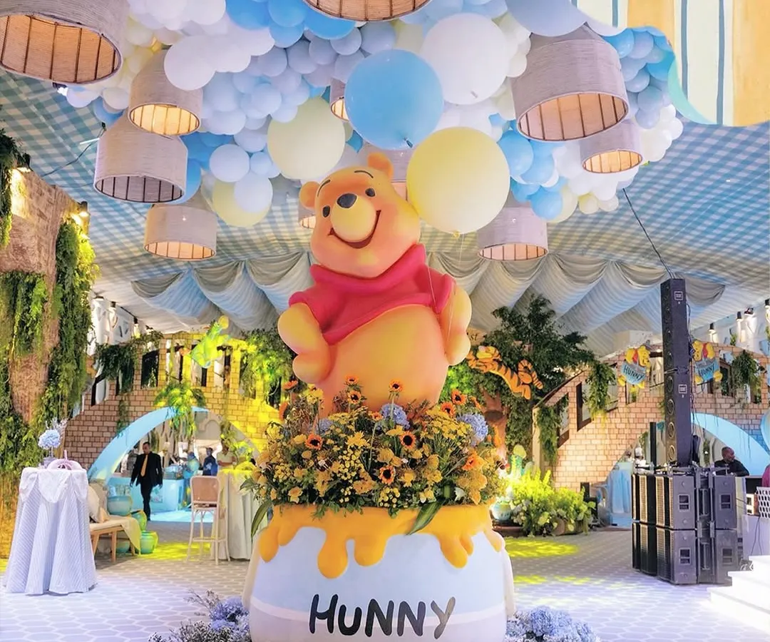 For a journey into the Hundred Acre Wood, I designed this towering Winnie the Pooh centerpiece emerging from a giant "Hunny" pot. The ceiling was transformed into a sky of blue and yellow balloons, making the entire space feel like a storybook page brought to life.