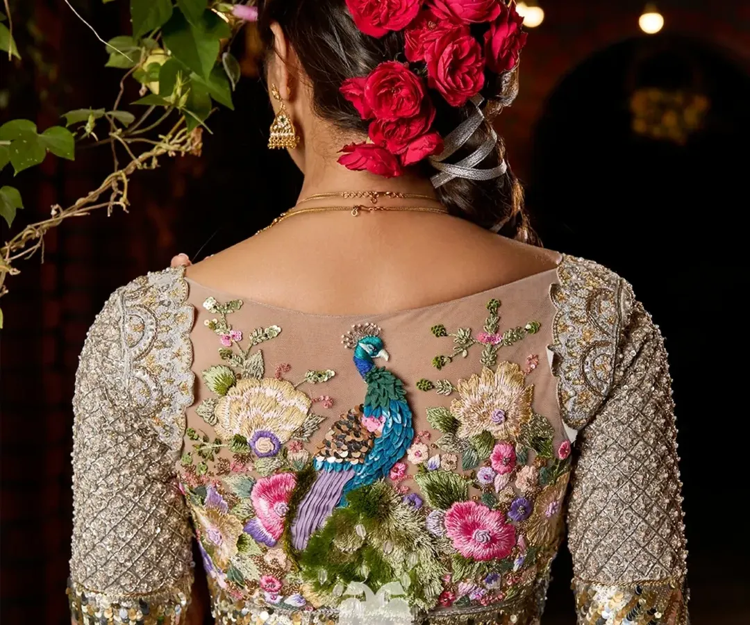 This is the Nemali Vanam blouse, a piece that captures the poetry of a peacock's dance. The back is set against a sheer base, allowing the intricate hand embroidery of lush florals and a regal peacock to become the centerpiece. The sleeves are embellished with katdana detailing, echoing the artistry of temple architecture.