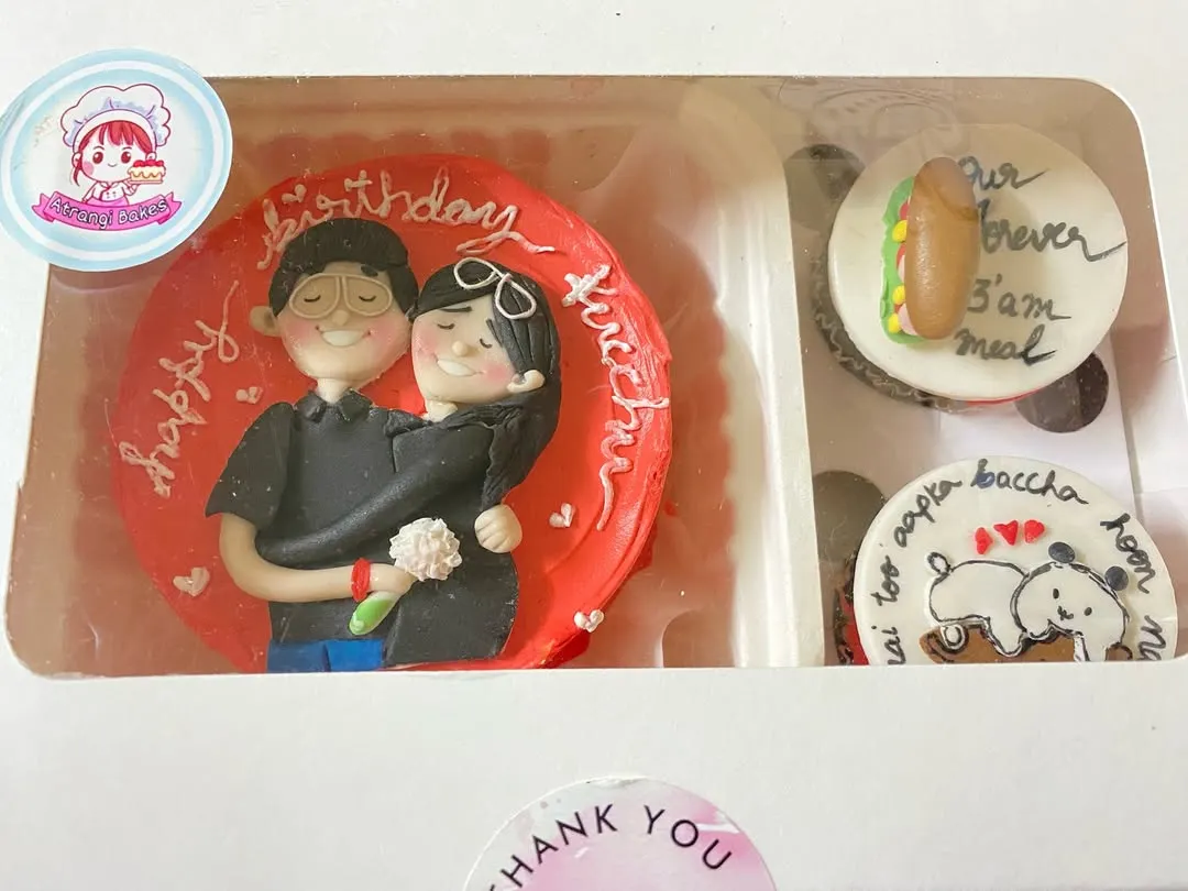 A close-up of one of our favourite bento and cupcake combos. This set features a hand-painted Nutella hazelnut bento cake with a couple's portrait, paired with cupcakes showing their inside jokes like "our forever 3 am meal".