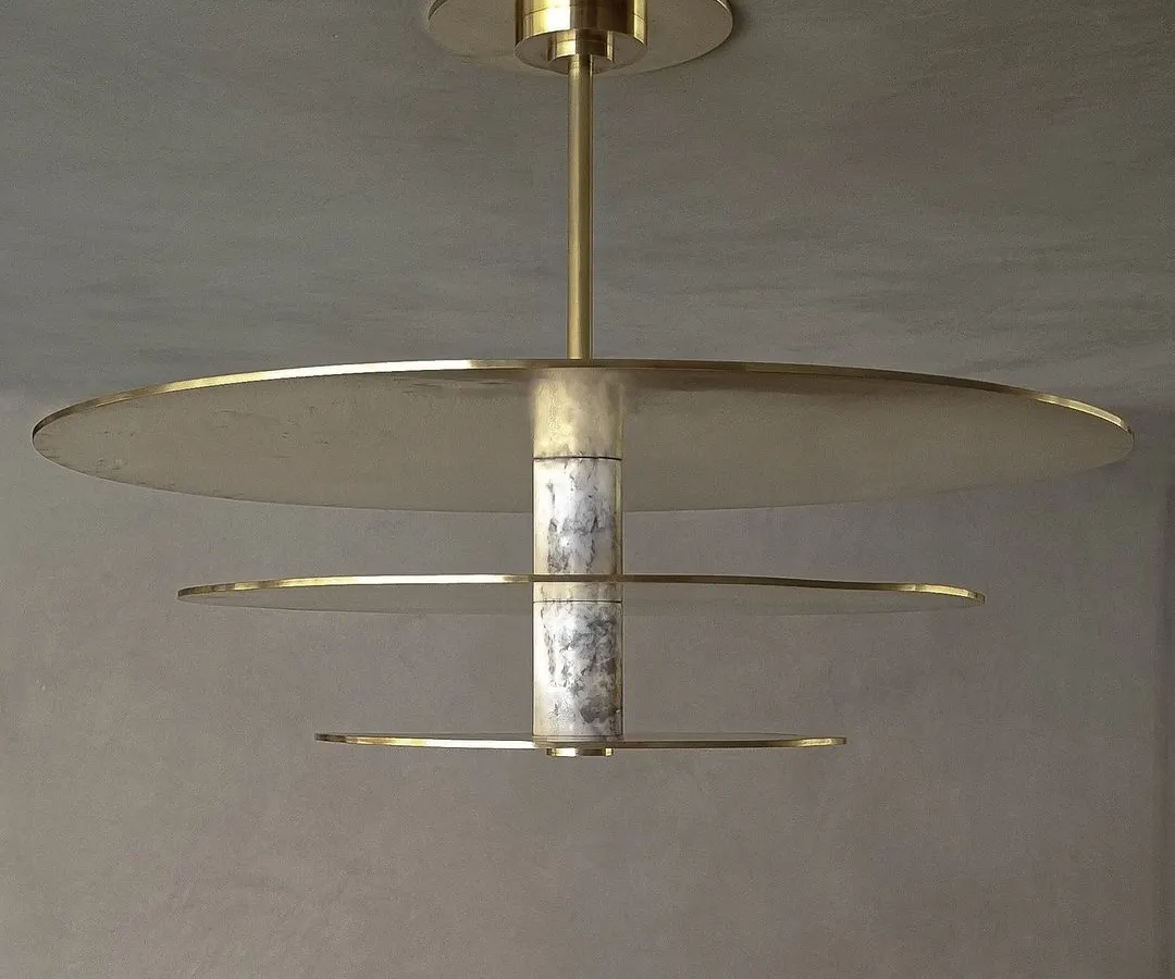 A detailed view of our custom ceiling light, where we explored the interplay between materials. The fixture combines cool, veined marble with the warmth of spun brass discs, creating a sculptural centerpiece for an entrance foyer.