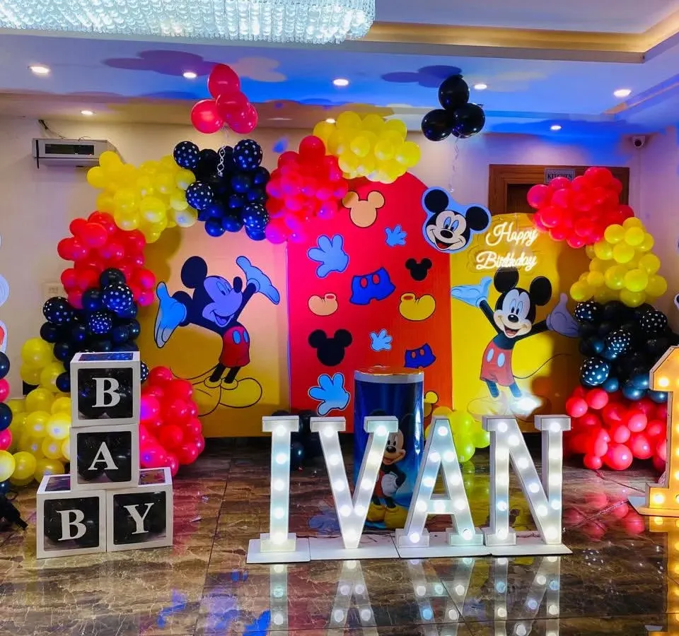 I love bringing cartoon themes to life, like this vibrant Mickey Mouse first birthday party. The setup includes a custom backdrop with character cut-outs, marquee letters spelling the name 'IVAN', and a colorful balloon garland.