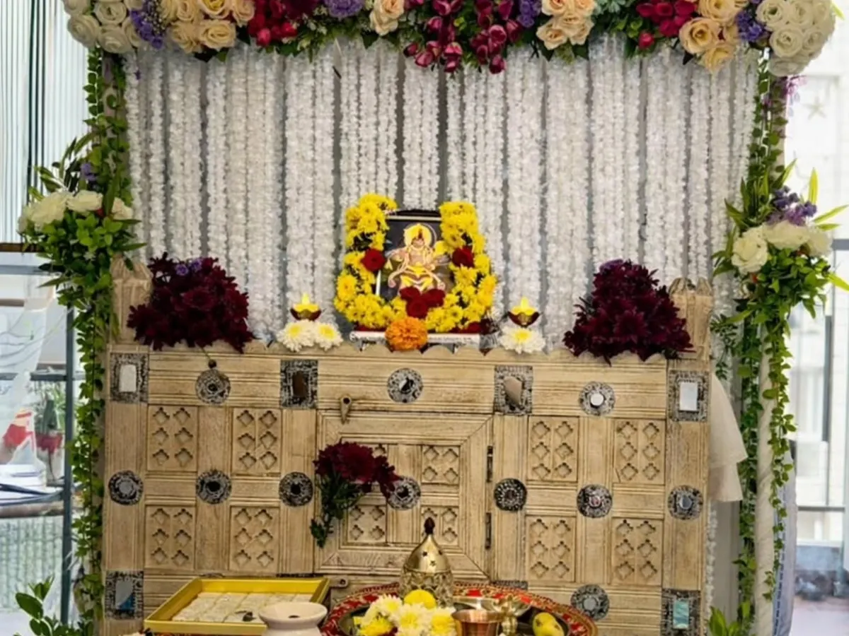 I designed this serene pooja corner for a client's home. The setup features a backdrop of delicate white rajnigandha strings, complemented by a lush arrangement of cream roses and deep purple flowers on a rustic wooden cabinet.