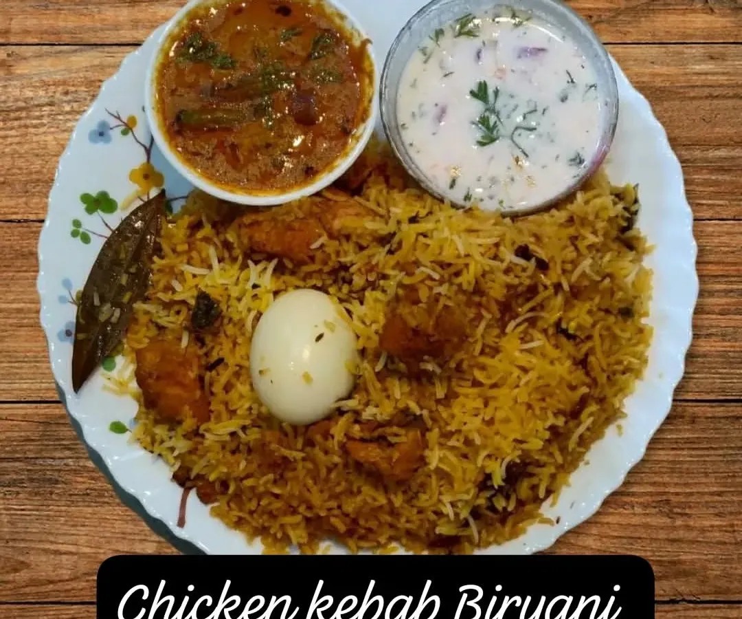 My homemade Chicken Kebab Biryani, plated and ready to be enjoyed. I make it with fragrant basmati rice, tender chicken kebabs, and a blend of spices, served with traditional mirchi ka salan and cooling raita.