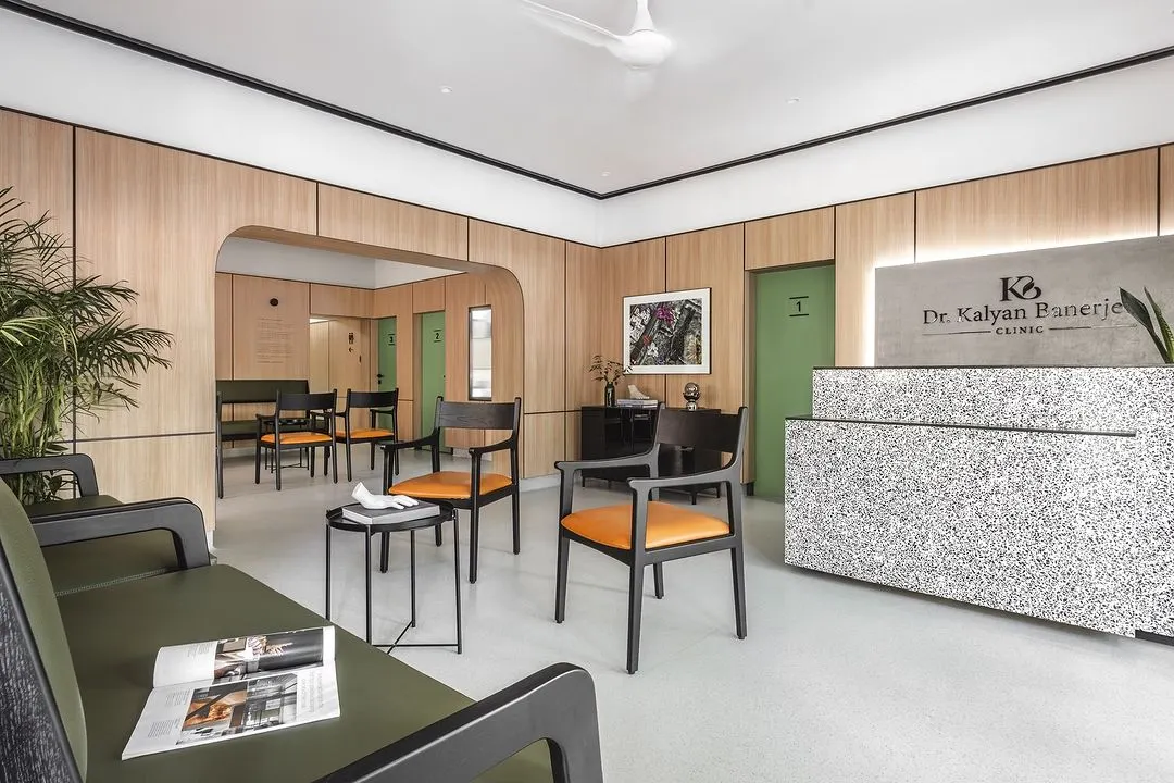 The reception and waiting area of Dr. Banerjee's Homeopathy Clinic. We used a minimalist approach with warm oak panels, a monolithic quartz desk, and clean lines to create a tranquil space that immediately puts patients at ease.