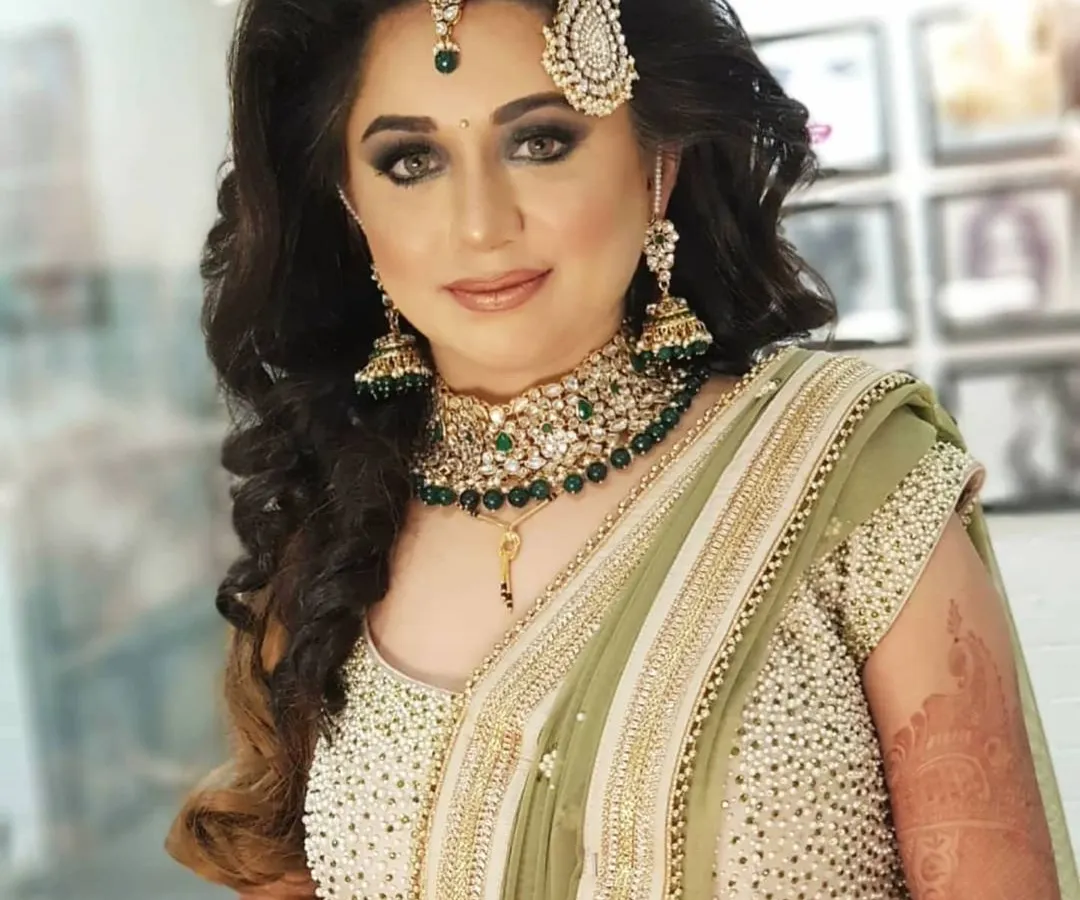 For this stunning bride's reception, we chose a classic smokey eye and a subtle nude lip. I used airbrush makeup to create a flawless, long-lasting base that looked perfect in photos and in person. The side-swept curls and passa completed her modern royal look.