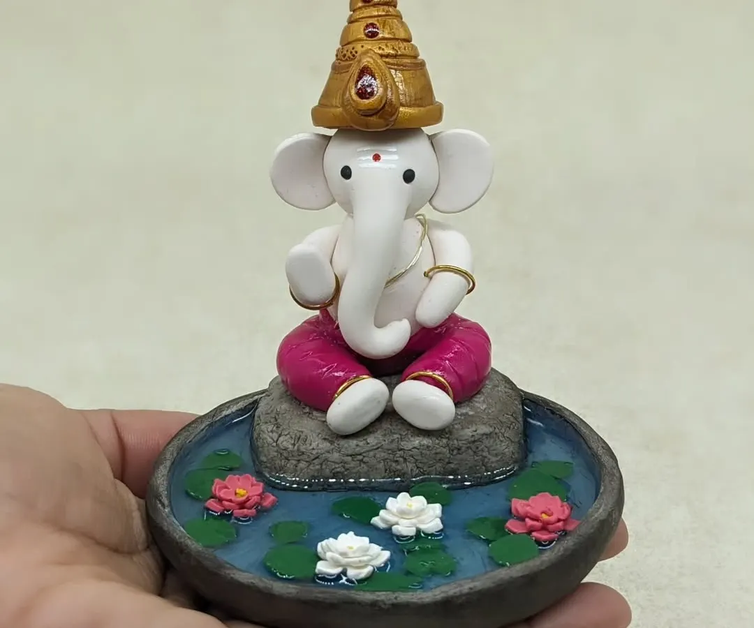 This is one of my favorite pieces to create. A miniature Ganesha, hand-sculpted from polymer clay, finding his peace in a serene lotus pond. Each tiny petal and the calm water effect is crafted to bring a sense of tranquility to your home.