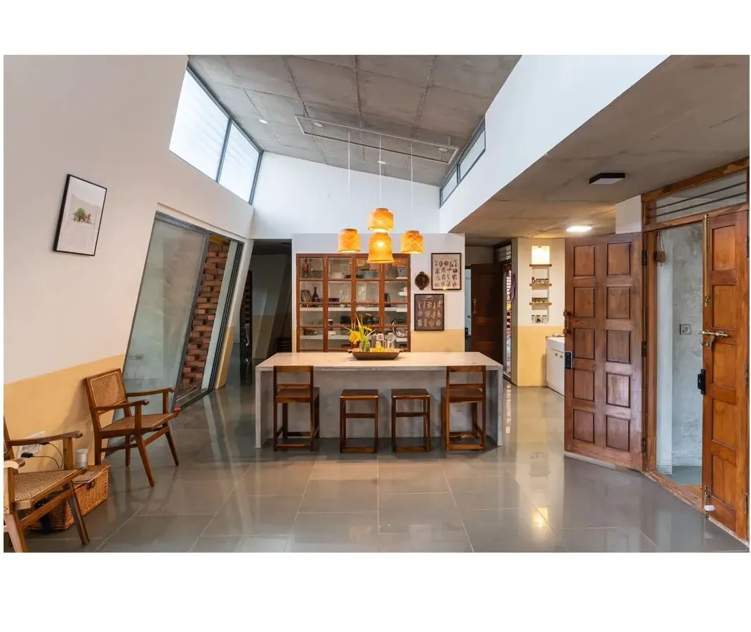 The heart of the Aamra house, where the kitchen and dining areas converge. This open-plan space is designed for gathering, featuring a polished concrete island, upcycled wood cabinetry, and an exposed concrete ceiling, reflecting our principle of material honesty.