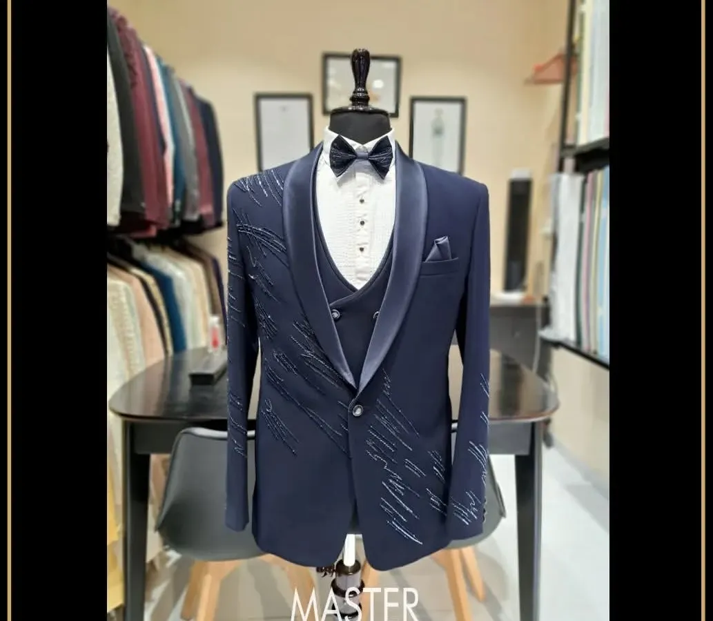 For the groom who wants to make a statement. This navy blue three-piece tuxedo features a unique shawl lapel and delicate crystal work, designed to make your special day even more memorable.