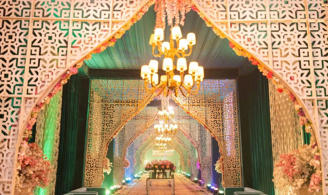 We make a powerful first impression with this grand wedding entrance. A long, dramatic walkway is framed by repeating white geometric arches and illuminated by a series of classic chandeliers, creating a spectacular tunnel of light and elegance for guests to walk through.