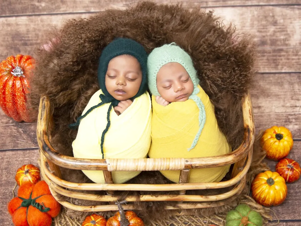 I specialize in newborn twin photography, and this autumn-themed setup is a client favorite. Here, two sleeping twins are swaddled snugly in a wicker basket, surrounded by colorful pumpkins and fall foliage.