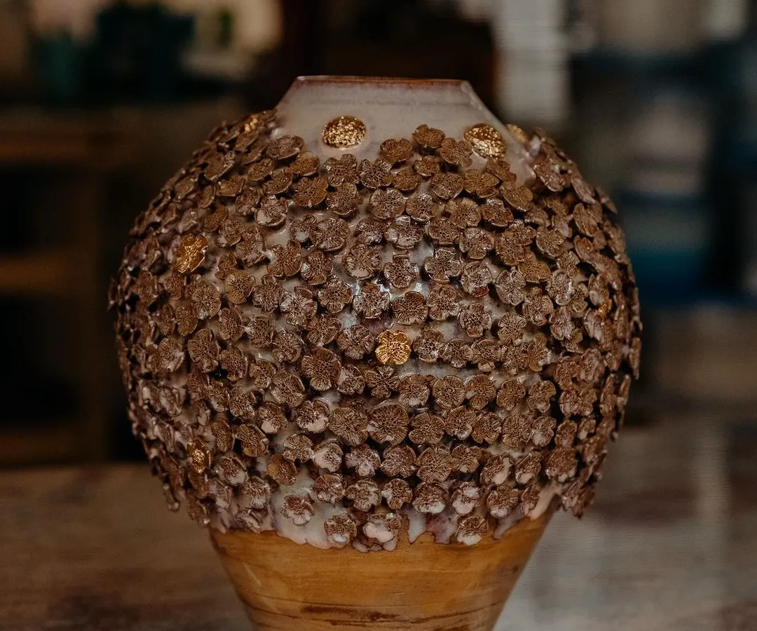 This is my 'Floral Grace' vase, a piece I am incredibly proud of. It is wheel-thrown and then adorned with hundreds of tiny, individually handcrafted clay flowers, with little touches of gold to catch the light.