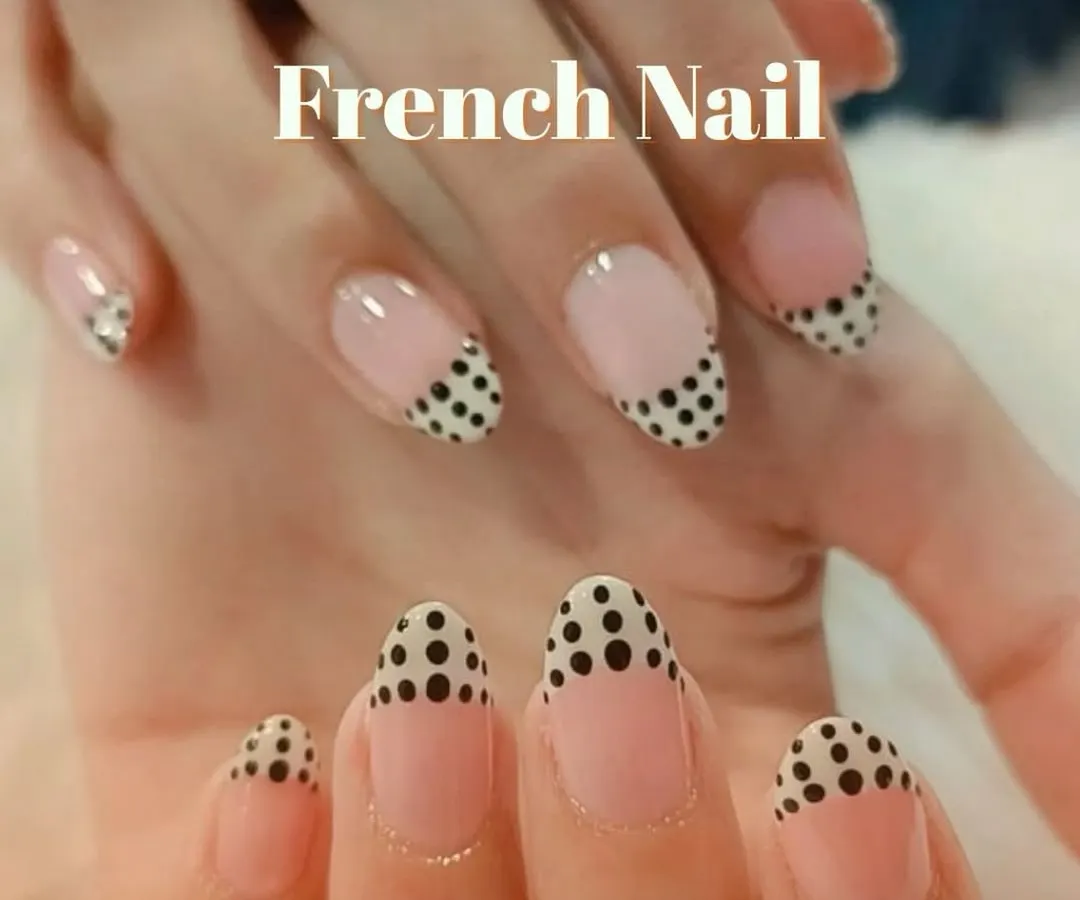 A playful and chic twist on a classic. These almond-shaped nails feature a modern French manicure with a fun black polka dot pattern on the tips for a unique style statement.