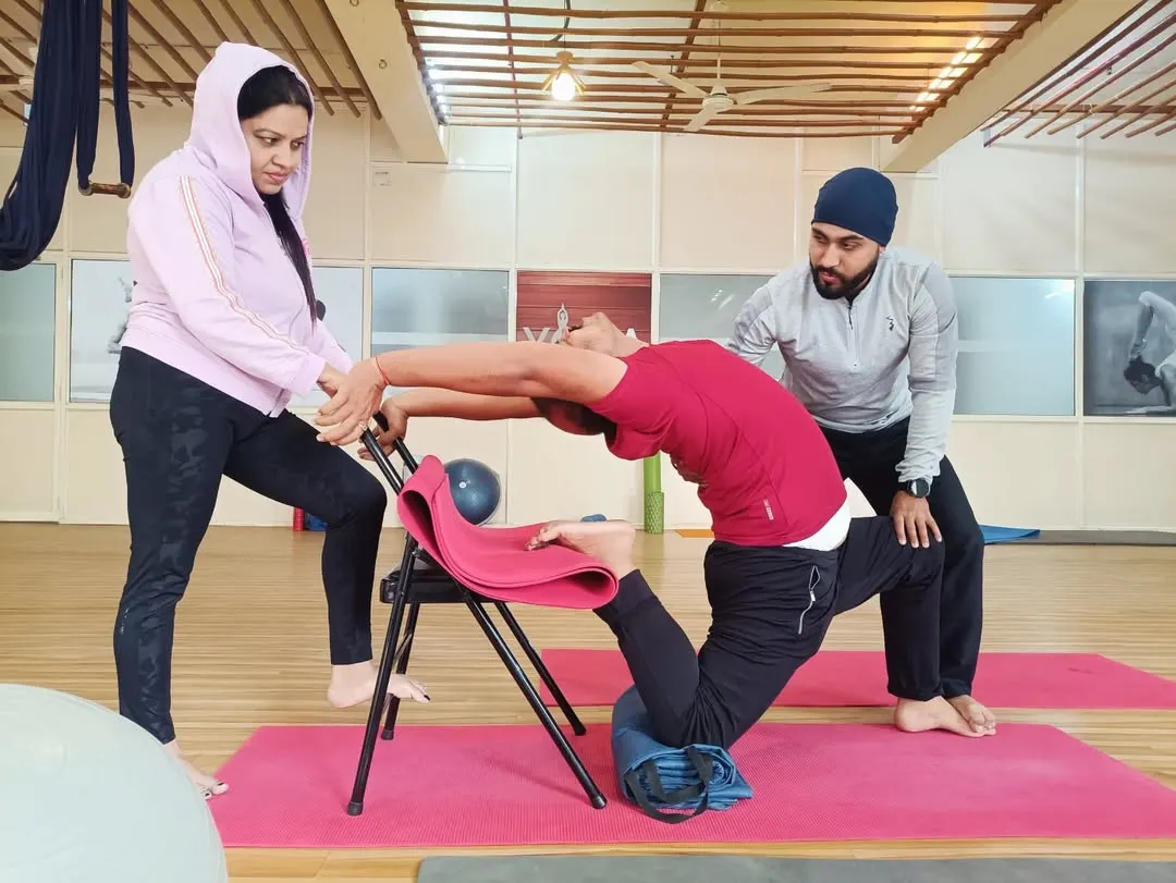 For many, deep backbends seem impossible due to stiffness or fear of injury. Here, I am assisting a student using a yoga chair for support, allowing them to safely open their spine and build confidence. My one-on-one therapeutic approach ensures that every pose is adapted to your body's specific needs.
