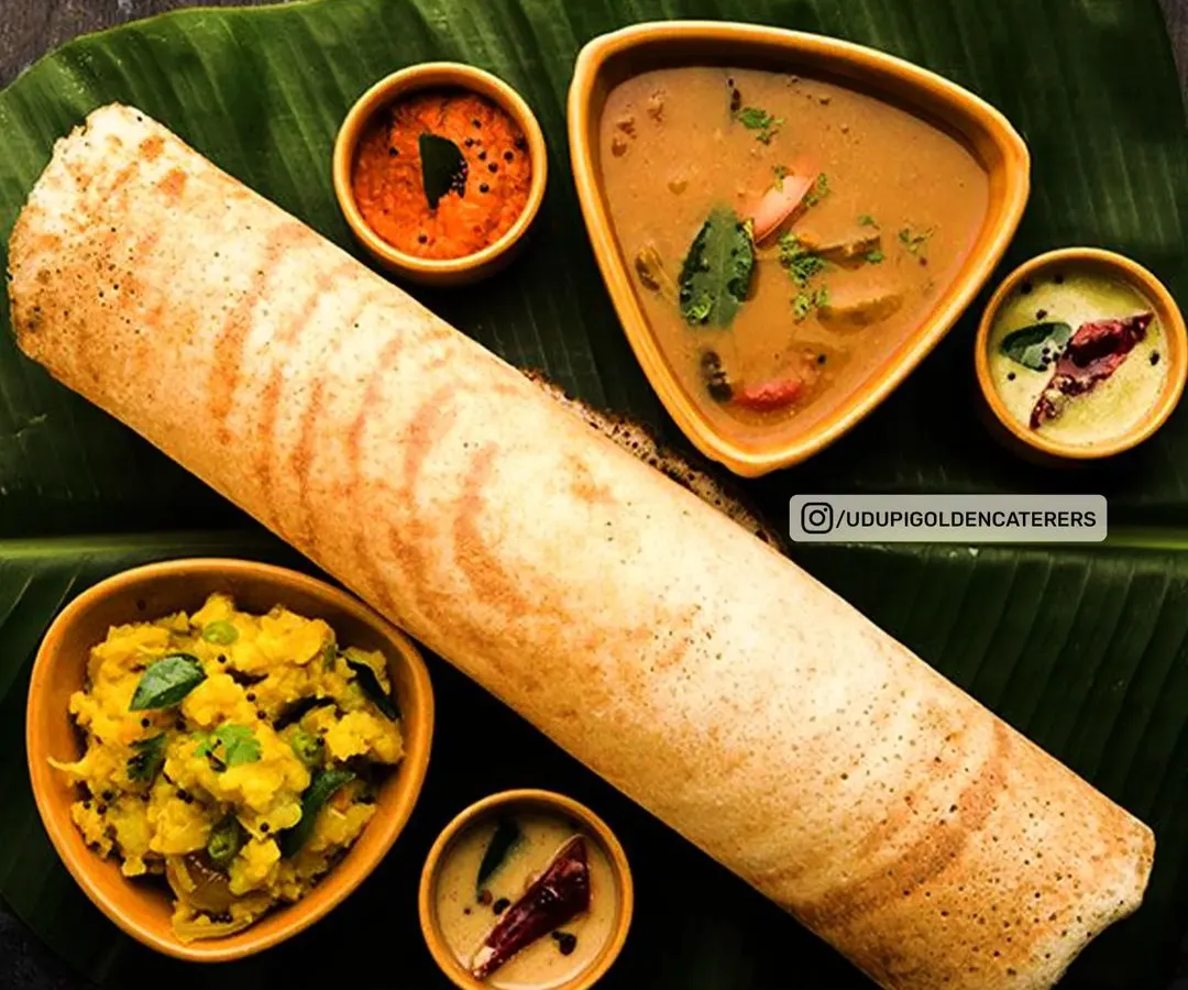 A classic South Indian Masala Dosa, served on a traditional banana leaf with fresh coconut chutney, spicy red chutney, and flavorful sambar. This is a highlight of our live dosa counters and breakfast menus.