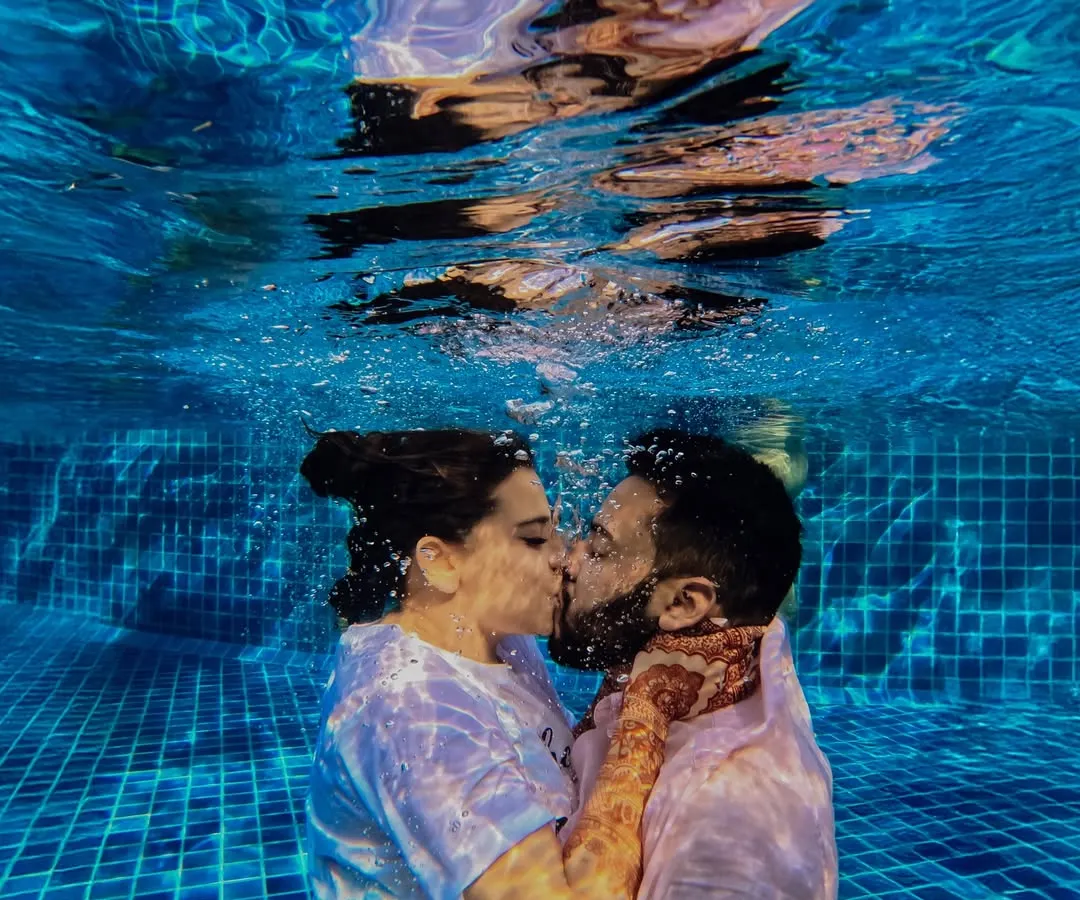 In a moment of pure, uninhibited joy, a couple shares an underwater kiss during their pool party in Thailand. It’s these unique, playful memories that make a destination wedding truly unforgettable.