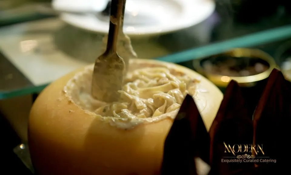 Our interactive Italian Pasta Studio in action. Here, fresh pasta is tossed in a large wheel of Parmigiano Reggiano, creating a rich, creamy sauce right before your guests' eyes. It's a theatrical culinary experience that always draws a crowd.