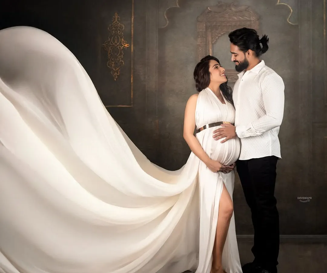 A beautiful moment between partners. I love capturing these intimate connections, with the flowing white gown adding a touch of elegance and drama to this maternity couple portrait against a classic studio backdrop.