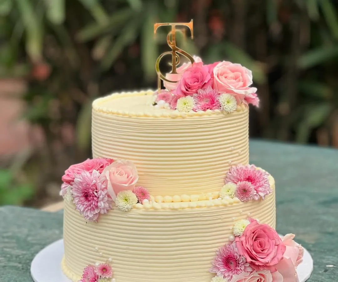 I love bringing your grand celebrations to life. This two-tiered custom cake, adorned with fresh pink roses and chrysanthemums, was designed to be an elegant centerpiece for a very special day.