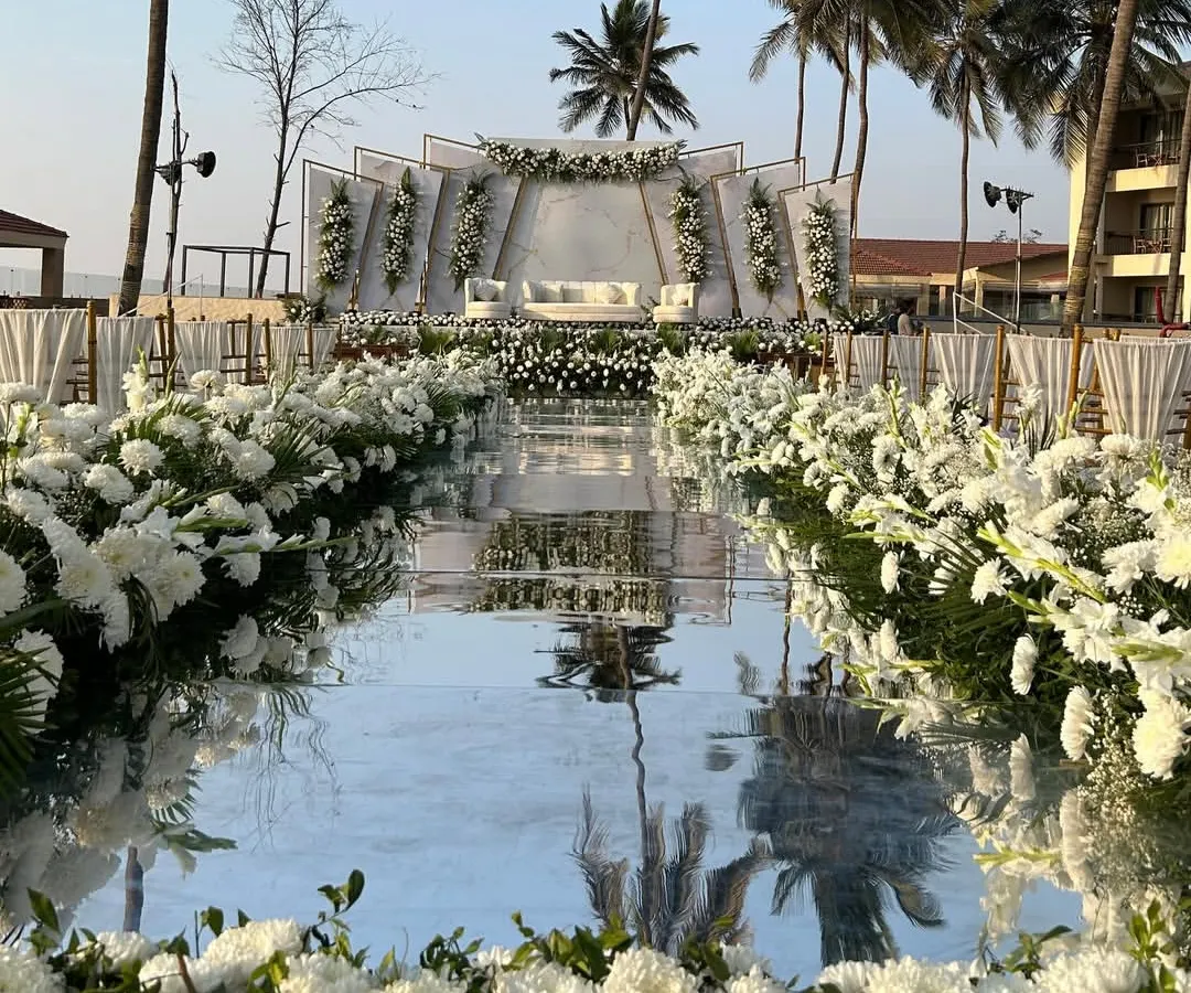 For this beachside wedding, I designed a stunning mirrored aisle that reflects the sky and the elegant white floral decor. This modern setup, with its clean lines and backdrop of palm trees, creates a serene and luxurious path for the couple's grand entrance.